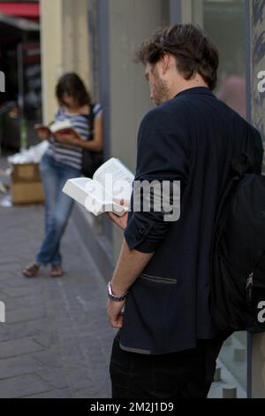 Paris, France - 9 août 2013 : deux jeunes adultes lisant des livres tout en s'appuyant sur un bâtiment Banque D'Images