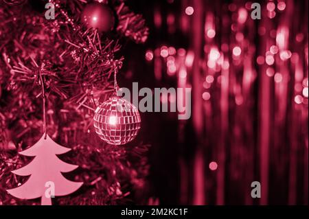 Une carte de Noël, un arbre de Noël, une boule disco sur fond de bokeh irisé. Toner Viva Magenta. Couleur tendance 2023 Banque D'Images