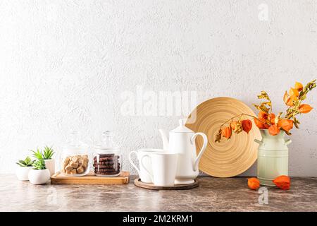 comptoir de cuisine en marbre avec cafetière et tasses, boîtes de sucre et café, verseuse avec fleurs séchées au mur texturé gris. un espace de copie Banque D'Images