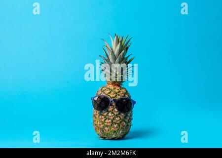 Fruits à l'ananas tendance avec lunettes de soleil sur fond bleu. Vacances d'été concept sain de vacances . Banque D'Images