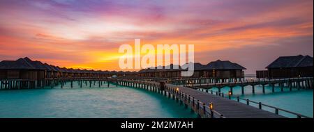 Nuit exposition longue paysage, sur l'eau villas aux Maldives. Magnifique panorama au coucher du soleil aux Maldives. Villas de luxe avec éclairage tamisé Banque D'Images