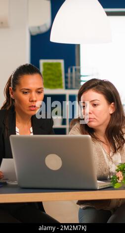 Bureau du directeur et directeur créatif travaillant dans un bureau moderne utilisant un ordinateur portable assis au bureau développant une idée de démarrage. Une équipe diversifiée de professionnels analysant les rapports financiers de l'entreprise à partir d'un ordinateur Banque D'Images