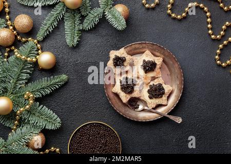 Caviar noir hors-d'œuvre étoiles sur une table noire décorée de noël horizontale Banque D'Images