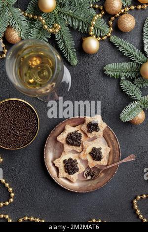 Caviar noir hors-d'œuvre étoiles sur une table noire décorée de noël vertical Banque D'Images