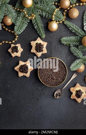 Caviar noir hors-d'œuvre étoiles sur une table noire décorée de noël Copyspace vertical Banque D'Images