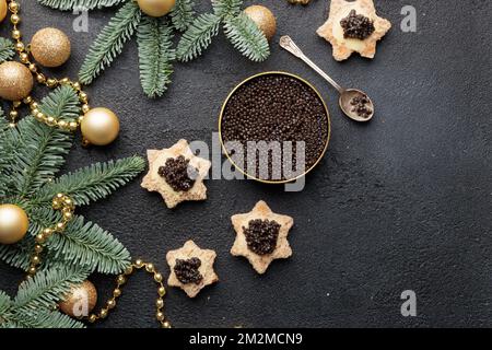 Caviar noir hors-d'œuvre étoiles sur une table noire décorée de noël Copyspace horizontal Banque D'Images