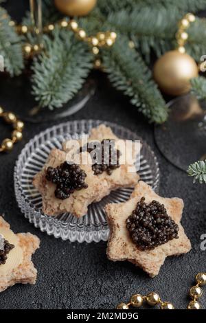 Caviar noir hors-d'œuvre étoiles sur une table noire décorée de noël vertical Banque D'Images