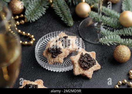 Caviar noir hors-d'œuvre étoiles sur une table noire décorée de noël horizontale Banque D'Images