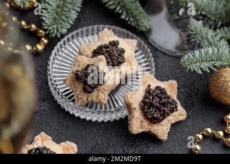 Caviar noir hors-d'œuvre étoiles sur une table noire décorée de noël horizontale Banque D'Images