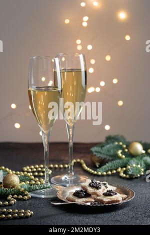 Caviar noir hors-d'œuvre étoiles sur une table noire décorée de noël avec champagne et bokeh vertical Banque D'Images