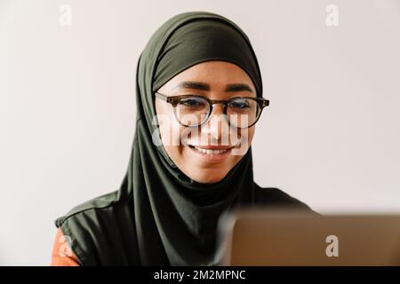 Jeune belle femme souriante dans hijab et lunettes travaillant avec ordinateur portable gros plan Banque D'Images