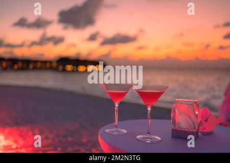 Deux cocktails avec plage floue et ciel de coucher de soleil coloré en arrière-plan. Luxe extérieur loisirs style de vie, détente et vibes romantiques Banque D'Images