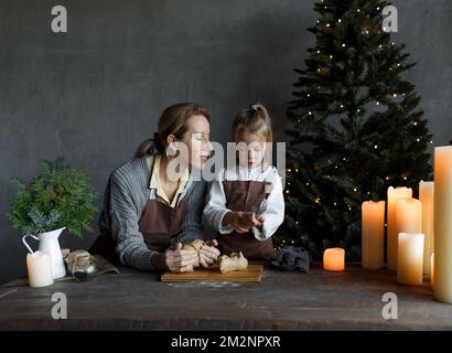 Une mère aimante avec une petite fille prépare un cadeau de Noël dans la cuisine. Préparation pour les vacances de Noël en famille. Banque D'Images