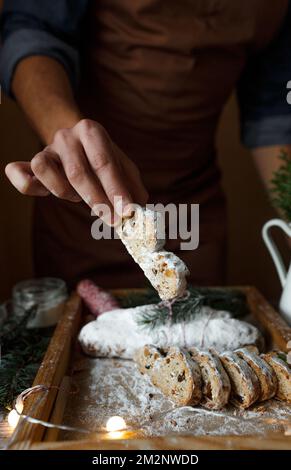 Le cuisinier tient un morceau de stollen de Noël dans sa main. Banque D'Images