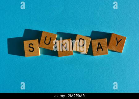 Dimanche, mot en lettres de l'alphabet de bois isolées sur fond bleu clair Banque D'Images