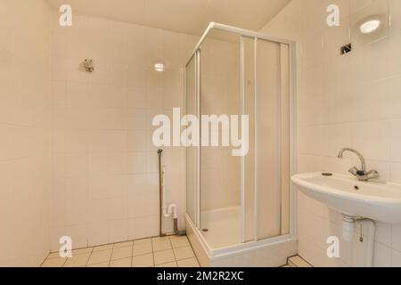 une salle de bains avec un lavabo, une cabine de douche et des toilettes dans le coin à côté de la baignoire au sol Banque D'Images