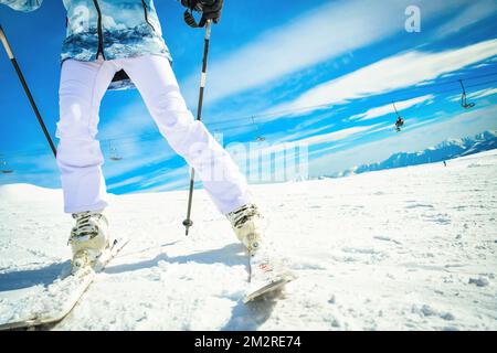 Femme skieuse en gros plan vue de fond lumineuse sur les chaussures de ski et les skis tout en s'arrête sur la sculpture en mouvement rapide Banque D'Images