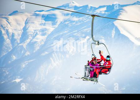 25th janvier, 2022 - Gudauri, Géorgie: Famille caucasienne de trois personnes assis sur le télésiège Profitez de la vue poser sur les vacances de ski d'hiver en plein air. De Noël Banque D'Images