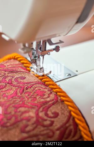 Machine à coudre moderne presse le pied et fil de bordure décoratif. Processus de couture. Banque D'Images