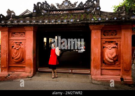 Femme asiatique en rouge se tient pour saluer les gens qui veulent entrer dans le pont couvert japonais. Seulement 1 personnes en photo. Banque D'Images