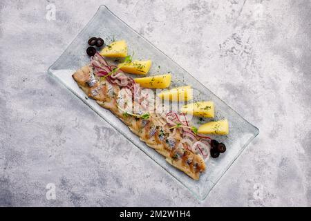 Hareng salé avec pommes de terre bouillies et herbes sur béton léger Banque D'Images