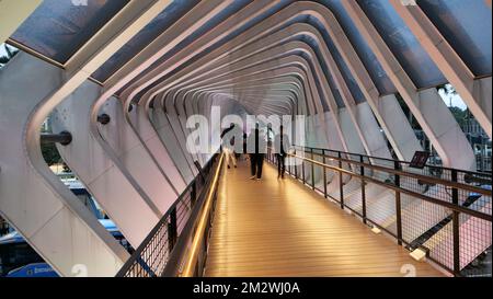 Piétons marchant sur le pont avec une série de portes inclinées à Sudirman à Jakarta, Indonésie Banque D'Images