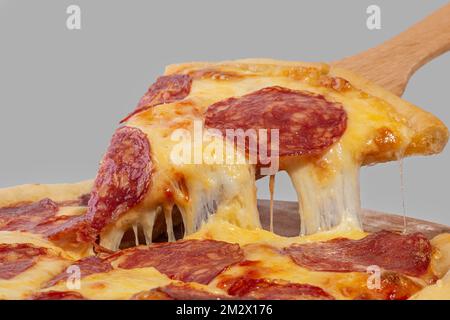 Tranche de pizza avec pepperoni et fromage à tartiner sur fond gris Banque D'Images