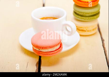 Macarons colorés avec café expresso sur table en bois blanc Banque D'Images