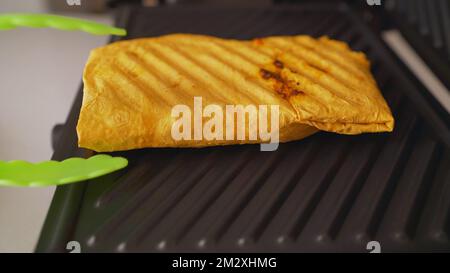 Faites griller les frites shawarma. Shaurma, petit pain pita grillé avec falafel, houmous, salade de frites et légumes dans une poêle. Banque D'Images