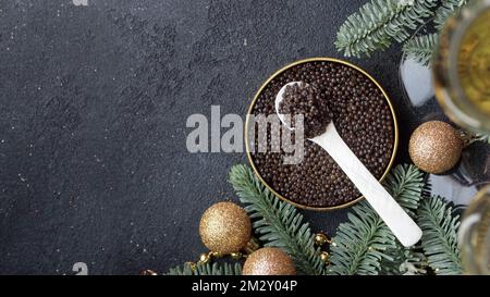 Caviar noir hors-d'œuvre étoiles sur une table noire décorée de noël bannière horizontale avec copyspace Banque D'Images