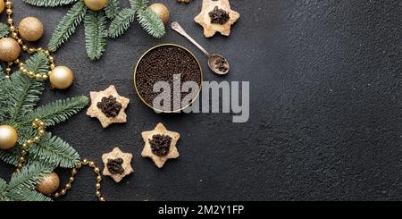 Caviar noir hors-d'œuvre étoiles sur une table noire décorée de noël bannière horizontale avec copyspace Banque D'Images