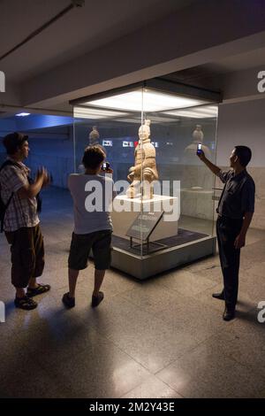 Les touristes chinois voient et prennent des photos sur leur téléphone portable de la figure archer à genoux, en terre cuite, excavée à partir de Pit 2 et maintenant exposé au touriste dans ce bâtiment. L'armée de terre cuite au musée du Mausolée de l'empereur Qinshihuang à Xi'an. PRC. Chine. (125) Banque D'Images