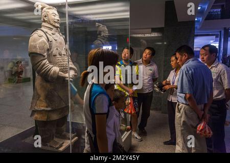 Groupe / famille / amis admirez et regardez la figure d'argile de terre cuite de haut classement chinois, excavée de Pit 2 et maintenant en exposition aux touristes dans ce bâtiment. L'armée de terre cuite au musée du Mausolée de l'empereur Qinshihuang à Xi'an. PRC. Chine. (125) Banque D'Images