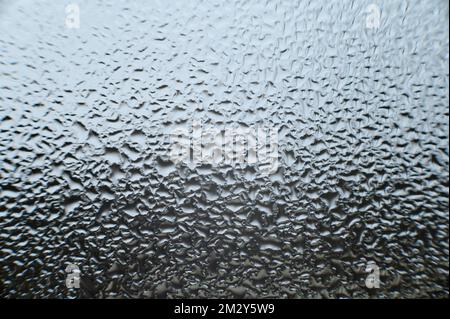grandes gouttes de rosée sur la fenêtre après condensation sur la fenêtre, la texture de l'eau tombe sur le verre. Banque D'Images