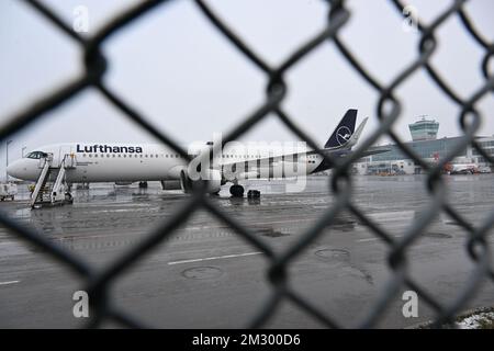 Freising, Germany. 14th Dec, 2022. A Lufthansa aircraft stands on the tarmac at Munich Airport, photographed through a wire mesh fence. Due to the danger of slippery conditions caused by freezing rain, aircraft were temporarily unable to take off and land at Munich Airport this afternoon. Credit: Felix Hörhager/dpa/Alamy Live News Banque D'Images