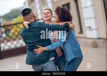 Compagnie de trois amis s'embrassant les uns les autres en plein air Banque D'Images