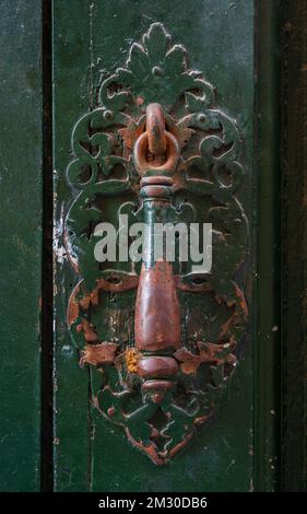 Vue rapprochée du knock de porte en laiton d'époque texturée isolé sur une ancienne porte en bois vert foncé, Montpellier, France Banque D'Images