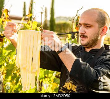 Un chef instructeur tient des pâtes faites à la main pliées sur une fourchette dans un vignoble Tenuta Torciano en Toscane Italie Banque D'Images