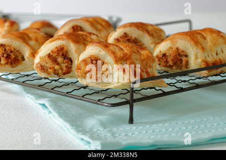 Petits pains à saucisse végétariens faits maison faits maison avec des poireaux de fromage, des oignons et de la chapelure rafraîchissants sur une grille de refroidissement en fil d'époque Banque D'Images