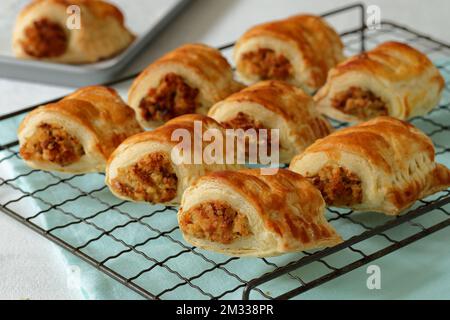 Petits pains à saucisse végétariens faits maison faits maison avec des poireaux de fromage, des oignons et de la chapelure rafraîchissants sur une grille de refroidissement en fil d'époque Banque D'Images