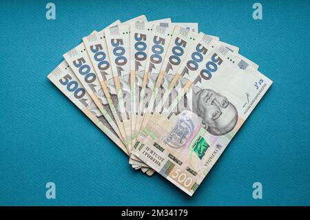 Argent comptant monnaie ukrainienne hryvnia cinq cents hryvnia mille billets et pièces monnaie revenus concept dollars sur un fond bleu Banque D'Images