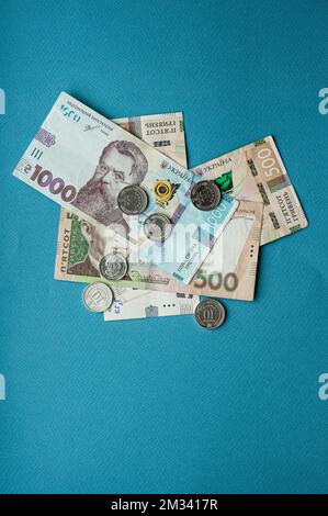 Argent comptant monnaie ukrainienne hryvnia cinq cents hryvnia mille billets et pièces monnaie revenus concept dollars sur un fond bleu Banque D'Images