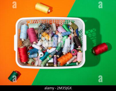 Une boîte avec des pièces de monnaie multicolores de différents fils sur un fond coloré Banque D'Images