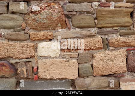 Vieux mur en pierre composé de pierres naturelles carrées de beige, ocre, rouge et marron. Fond de texture de mur de pierre Banque D'Images