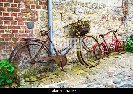 Vélo rouillé sur mur de briques dans la rue de la ville médiévale de Durbuy, Belgique Banque D'Images