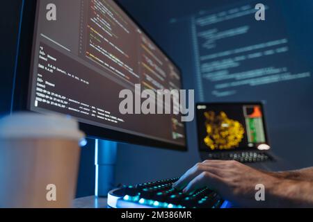 Pas d'image de la main masculine d'un ingénieur logiciel assis à table devant un grand écran de pc, dactylographiant et composant un script d'application, travaillant dans une société de science des données. Mise au point sélective Banque D'Images