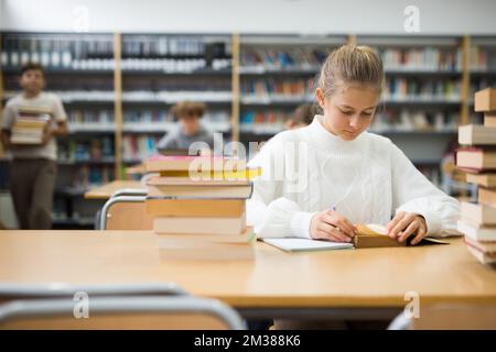 Jeune fille se préparant pour des examens en bibliothèque Banque D'Images