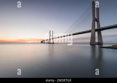 Arrière-plan avec lever de soleil coloré sur le pont de Lisbonne. Le pont Vasco da Gama est un point de repère et l'un des plus longs ponts du monde. réseau local urbain Banque D'Images