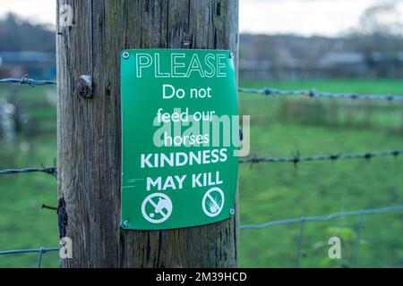 Panneau vert sur le poste de fencepost avertissant les gens de ne pas nourrir les chevaux en raison des risques d'étouffement, Angleterre, Royaume-Uni Banque D'Images