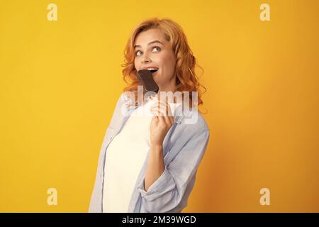 Portrait de mode jeune femme fraîche avec de la crème glacée sur fond jaune. Jeune fille hipster cheeky mangeant une glace à coller. Banque D'Images